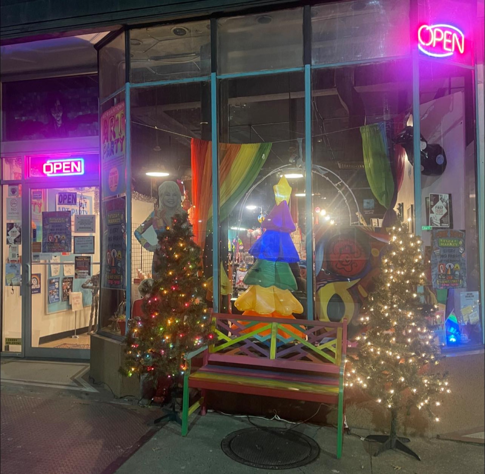 Storefront at night with the rainbow tree and OPEN sign